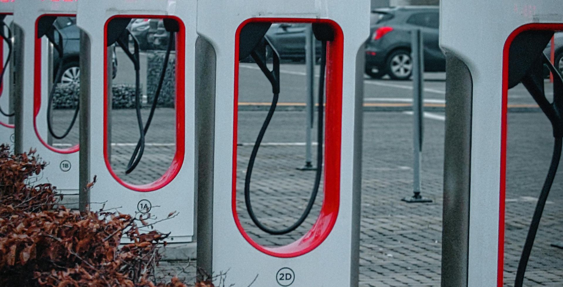 Line of Tesla charging stations in a misty urban environment, ready for electric vehicles.